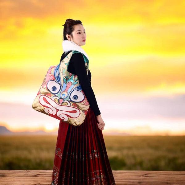 woman holding colorful bag with stylized animal face on it. 