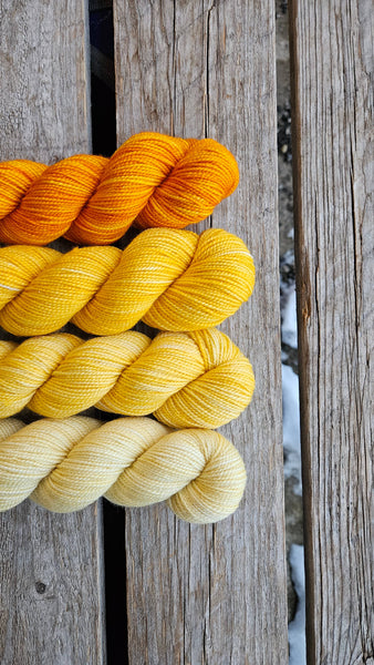 four skeins on wooden background in shades of golden yellow