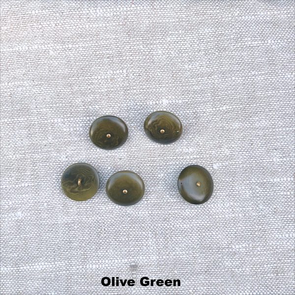 Five olive green corozo nut buttons on a textured grey fabric.
