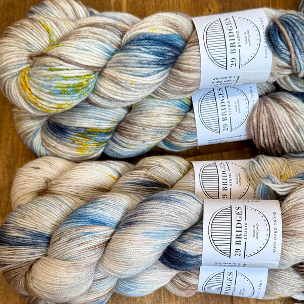 six skeins of yarn with labels on a wooden surface