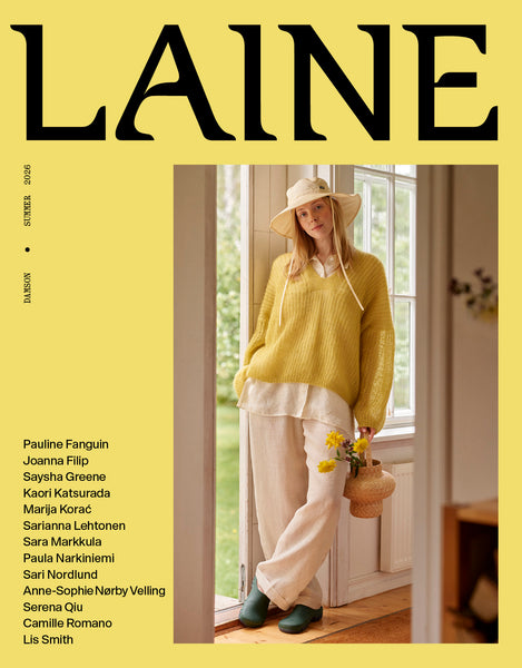 Magazine cover with a person in a yellow sweater standing by a window, featuring the brand 'Laine'.