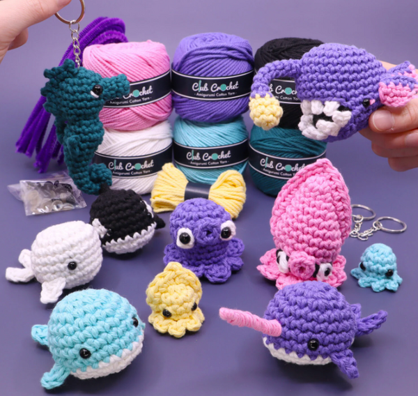 Collection of colorful crochet animals and yarn on a purple background