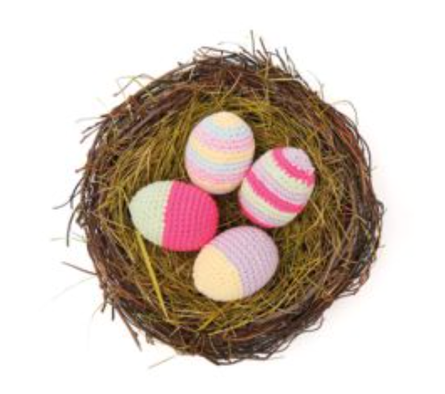 Nest with pastel-colored crocheted eggs on a white background