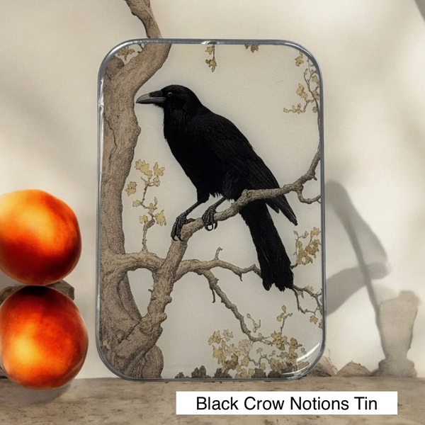 black crow perched on branch on a tin 