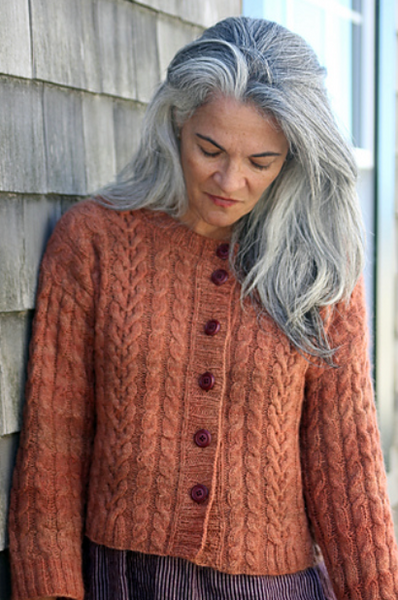 Woman wearing a brown knitted cardigan with a wooden wall background