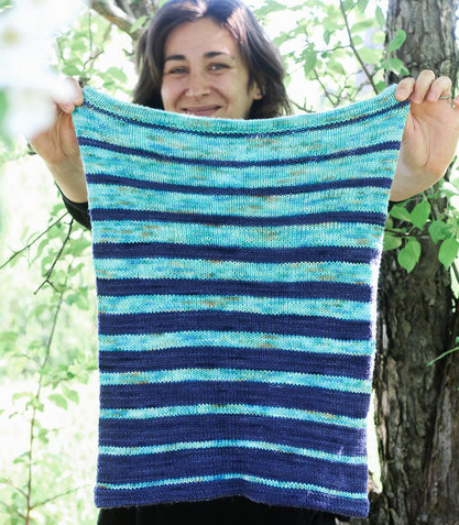 Woman holding a cowl in front of her.  The cowl is in Blue and light blue stripes.