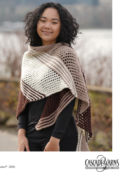 A woman standing wearing a shawl in the colors cream, brown and dark brown